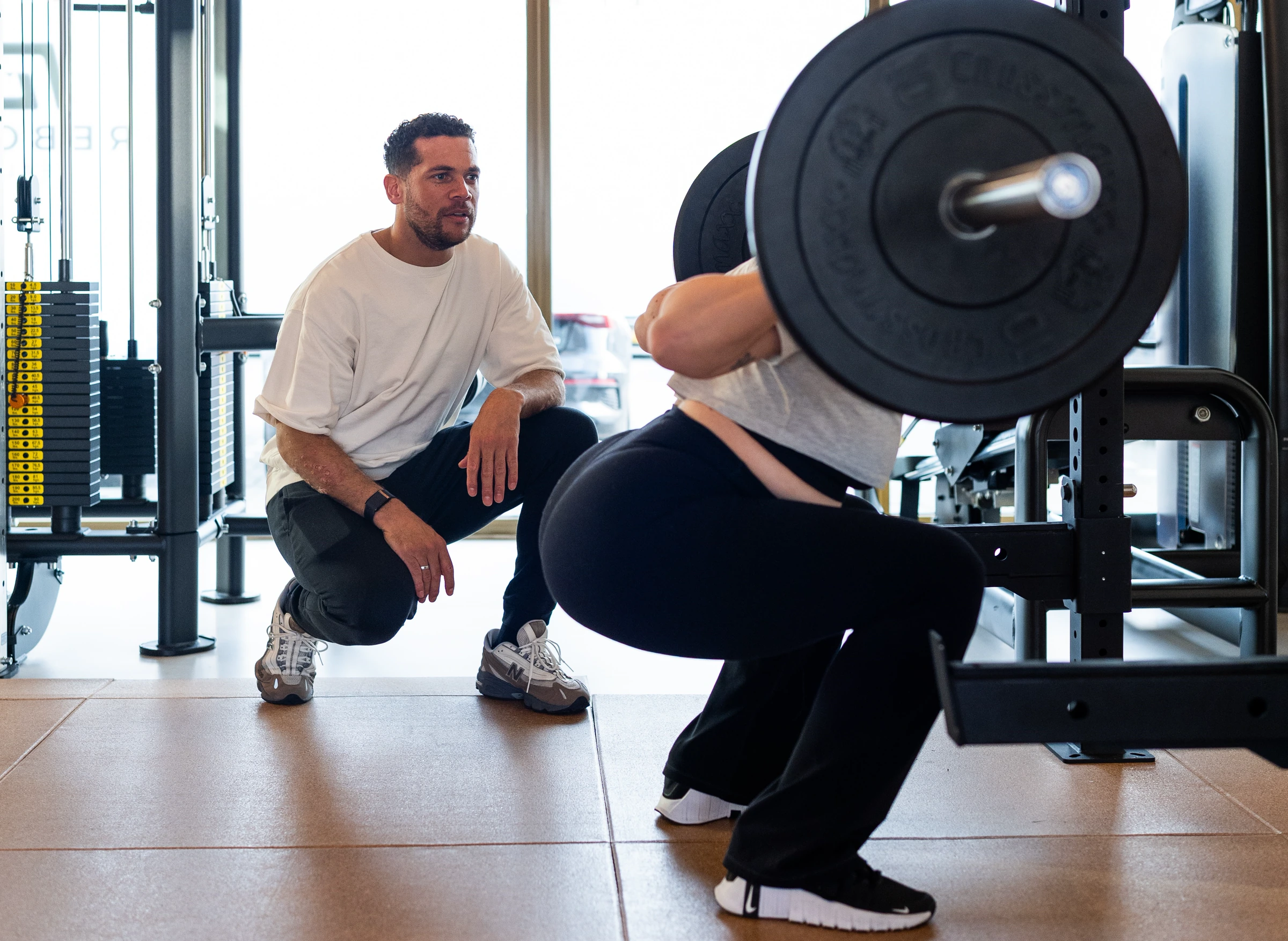 Coach begeleidt een squat tijdens een training bij Watchman Gym in Capelle aan den IJssel